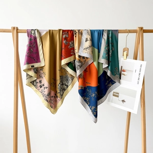 Detailed view of floral silk scarves in vibrant colors hanging on a wooden hanger
