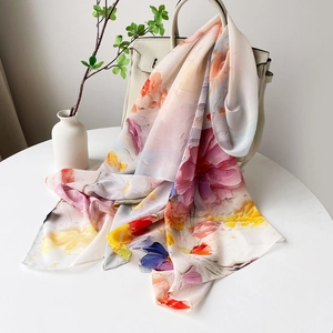 Détail d'un foulard en satin fleuri drapé sur un sac montrant sa texture et son imprimé