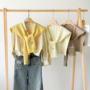 Close-up of hollow knit shawls in yellow, beige and brown with delicate weave details