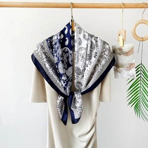 Detailed view of large square satin scarf with paisley prints and geometric patterns