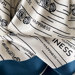 Détail macro d'un foulard en soie avec imprimé rose et lettrage Happiness élégant
