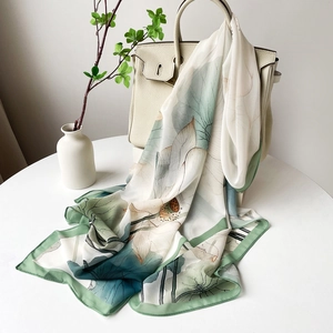 Détail d'un foulard en soie à imprimé lotus drapé sur un sac à main de luxe en cuir blanc