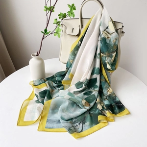 Détail du foulard en soie à motif feuilles vertes et ourlet jaune sur sac à main