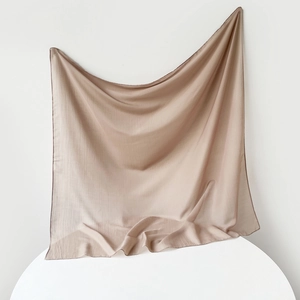 Macro shot of light brown muslin headscarf fabric draped elegantly on a pedestal