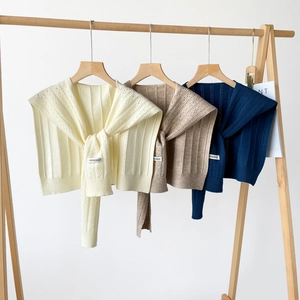Three colors of knitted hollow shawl collars displayed on wooden hangers
