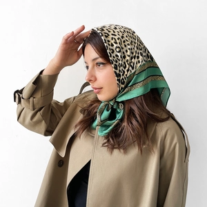 Detailed view of satin square scarf with leopard print and green border worn as a headwrap