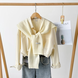 Detail of light yellow knit shawl with hollow crochet texture over a button-up shirt