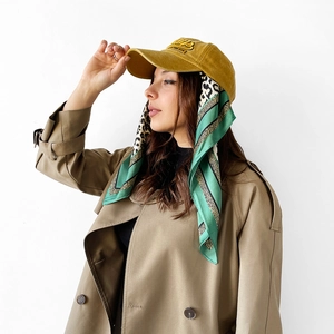 Detail view of ginger yellow baseball cap featuring elegant leopard print silk scarf trim