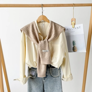 Detailed view of beige hollow-knit shawl with BONOGEED label on yellow cotton shirt