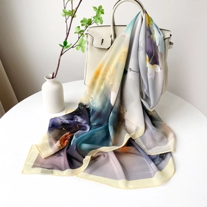 Détail d'un foulard en soie à fleurs artistiques drapé sur un sac à main blanc élégant