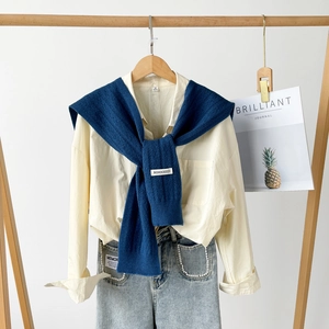 Detailed close-up of dark blue cable knit shawl over white shirt with pearl denim jeans