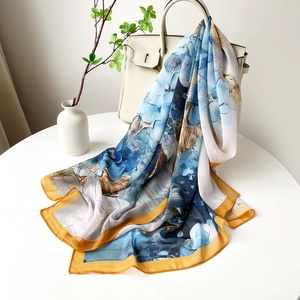 Texture détaillée de l'écharpe en satin bleu et or drapée sur un sac de luxe
