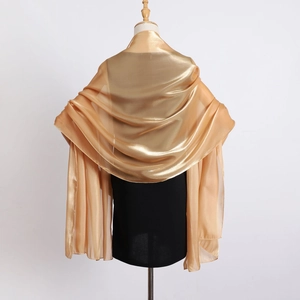 Detail view of a champagne gold organza shawl with silky metallic shine on a mannequin