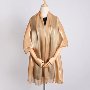 Detailed view of elegant gold organza shawl with metallic finish on a wooden mannequin