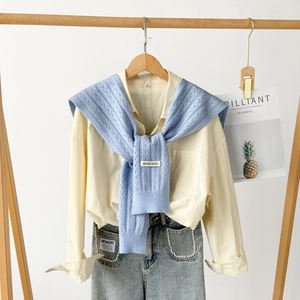 Detail of light blue hollow knit shawl with brand label on a classic shirt