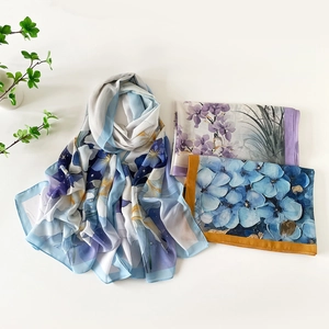 Mise à plat de foulards en soie aux motifs floraux bleus et violets et décorations vertes