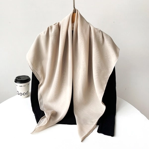 Close-up of lightweight champagne silk scarf with subtle sheen on a dark top