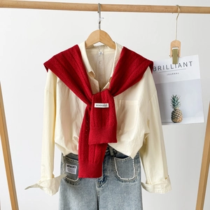 Detailed close-up of a red hollow knit shawl paired with a pearl-studded denim jeans pocket