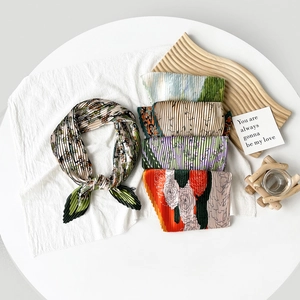 Detail of pleated satin square scarves in assorted floral and artistic prints