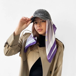 Fashionable styling detail of a purple floral satin headscarf worn under a grey cap