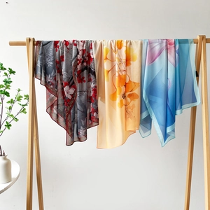 Vue détaillée de trois écharpes en soie aux motifs floraux sur un support en bois