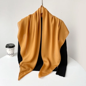 Detail of vibrant ginger yellow chiffon scarf draped over a black knit top in soft light