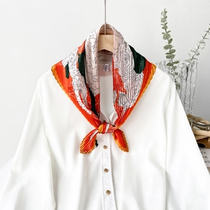 Detail of pleated silk scarf with floral print tied on white shirt for office style
