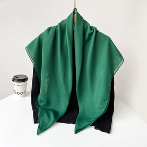 Detail view of the lightweight green chiffon scarf featuring soft pleated fabric texture