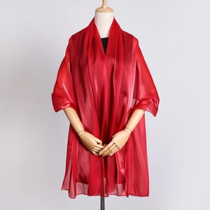 Detail of red organza long scarf showing sheer texture and silk gloss on a wooden mannequin