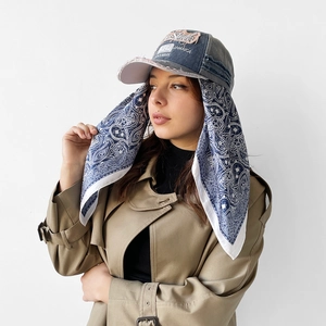Detail of grey distressed denim baseball cap with paisley silk scarf and embroidery