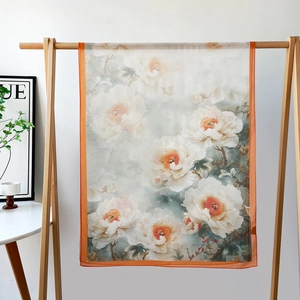 Détail d'une écharpe légère en soie à imprimé floral avec des bords orange vif sur un cintre