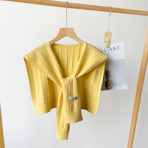 Detailed knit texture and brand label on a bright yellow minimalist shawl for women
