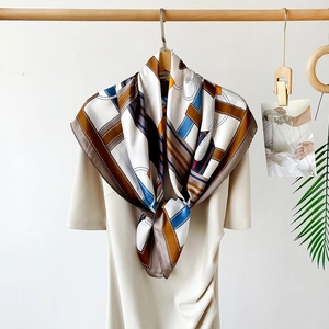 Detail of a geometric chain print satin scarf styled on a beige dress for a chic look