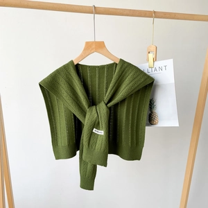 Detail of dark green knitted shawl with vertical stripe texture and branding tag