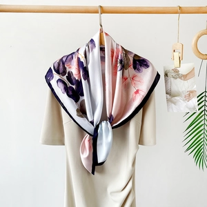 Detail of elegant pink leaf print satin scarf draped over a beige dress with a smooth texture