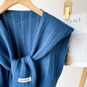 Close-up of blue hollow-out knitted shawl with delicate pointille texture and brand label