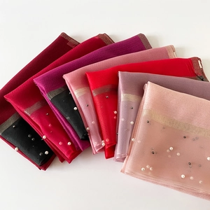 Détail de foulards en soie légère avec décorations de perles et bordures brillantes