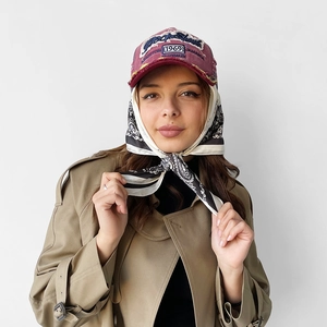 Close-up of vintage burgundy baseball cap with frayed brim and patterned silk headscarf