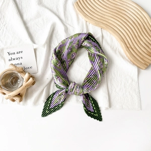 Detail of a purple floral pleated satin scarf tied on a wavy wooden tray with decor