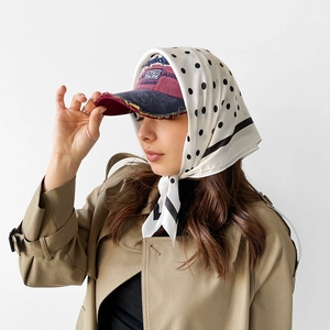 Close-up of black polka dot silk scarf styled with a vintage 1969 embroidery baseball cap