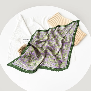 Close-up of pleated satin scarf with purple floral patterns and fine green border