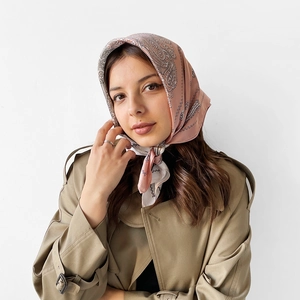 Detail of paisley satin headscarf in pink and beige worn with a classic trench coat