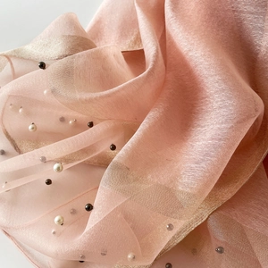 Gros plan sur l'écharpe rose avec rayures dorées et perles décoratives élégantes