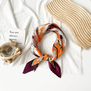 Detail of artistic pleated satin scarf with abstract orange and purple floral print