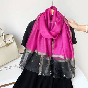 Détail de l'écharpe rose rouge avec ourlet en tulle noir, perles et bordure dorée
