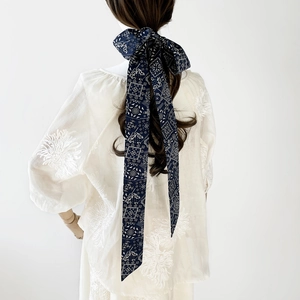 Detailansicht eines dunkelblauen Baumwoll-Haarbands mit Blumenmuster als Schleife gebunden