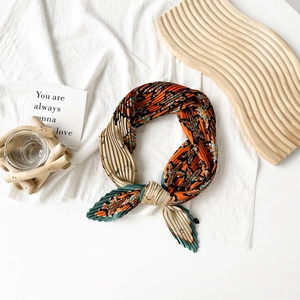 Detail of pleated satin neckerchief with orange and green floral patterns on tray