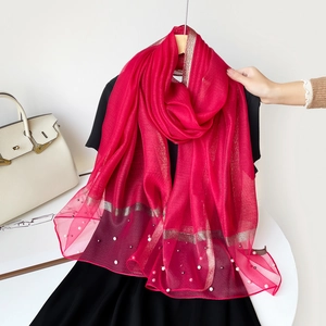 Détail de l'écharpe en soie rouge rose avec rayures dorées et perles décoratives