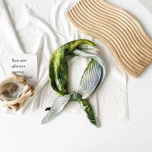 Detail of green and white gradient pleated scarf with 100% polyester fabric texture