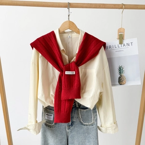 Women cross knit shawl wrap over cream shirt and pearl decorated denim jeans outfit
